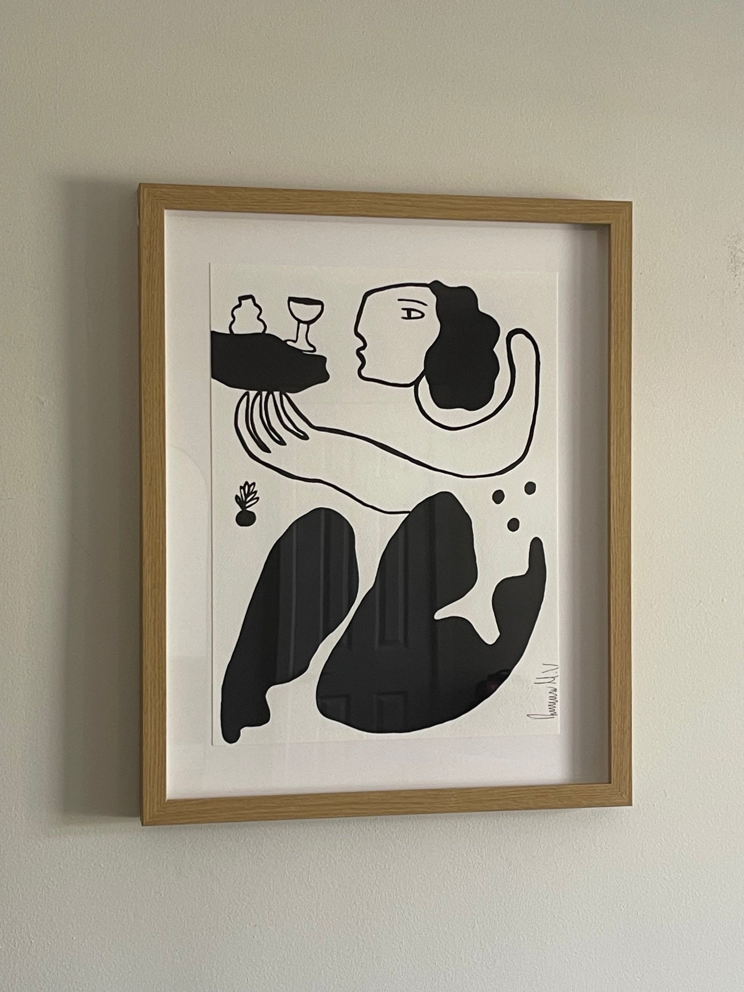 Framed black and white abstract artwork on a beige wall